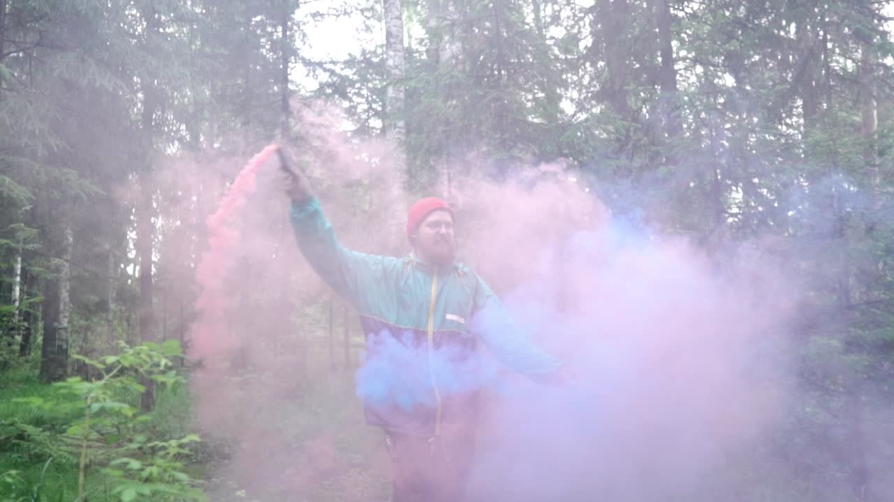 hombre con coloridas bombas de humo en un bosque