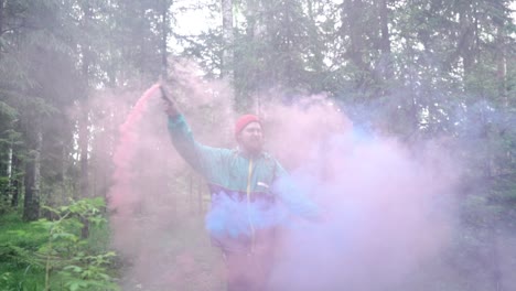 man with colorful smoke bombs in a forest