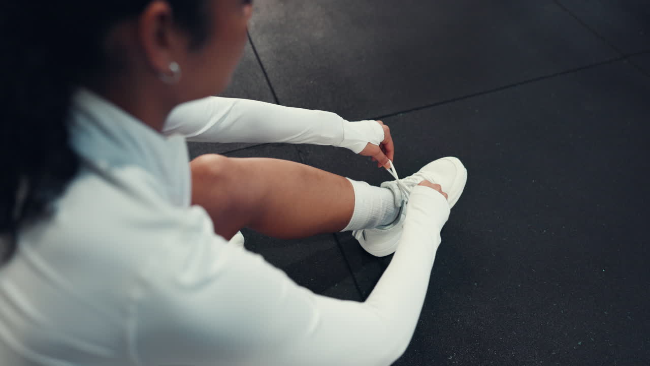 Woman tying her shoelaces on the gym floor