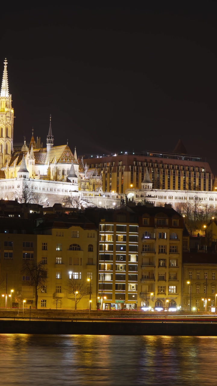 Budapest’s Buda Castle, Fisherman’s Bastion, and Matthias Church stand illuminated along the Danube River at night, displaying historic Hungarian architecture in the city’s medieval castle district.