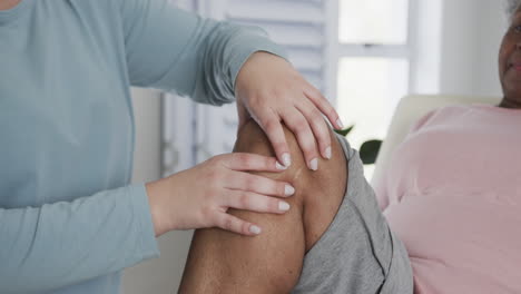 caucasian female physiotherapist checking knee of senior woman, copy space, slow motion