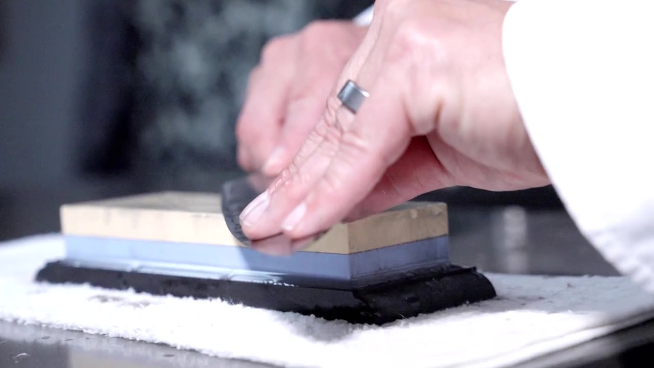 An up-close following action shot of a chef sharpening his knife with precision. Perfect for culinary content, showcasing essential knife skills and the artistry of kitchen preparation.