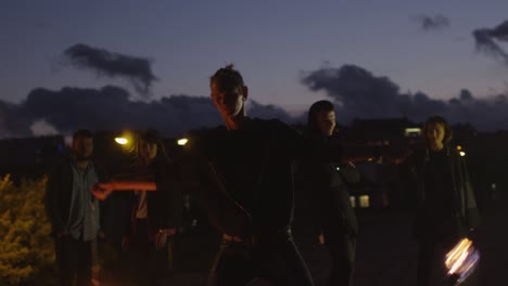 male artist performing fire show outdoors at evening time.