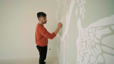 el artista está decorando las paredes con dibujos en la habitación de los niños. pintura de arte de las paredes en la casa nueva. trabajos de reparación.