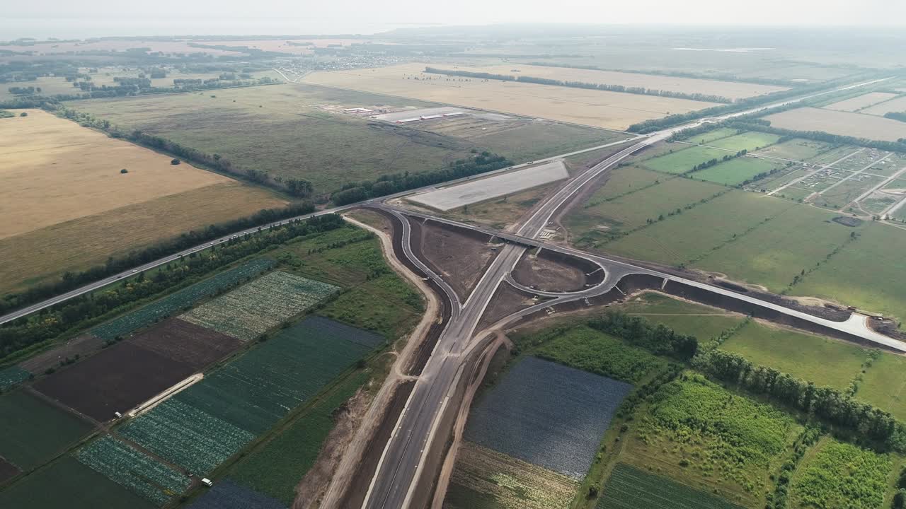 Aerial view of the traffic intersection. Transport interchange of highways. Interchange under construction in the fields. Beautiful view