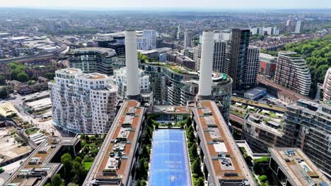 dynamic drone fly-through between battersea power station’s iconic chimneys in london, showcasing industrial design, rooftop gardens, skyline views, and the ever developing area