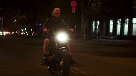 Stylish,-brutal-motorcyclist-drives-a-bike-in-the-city-with-bright-headlight-by-street-road-in-fog