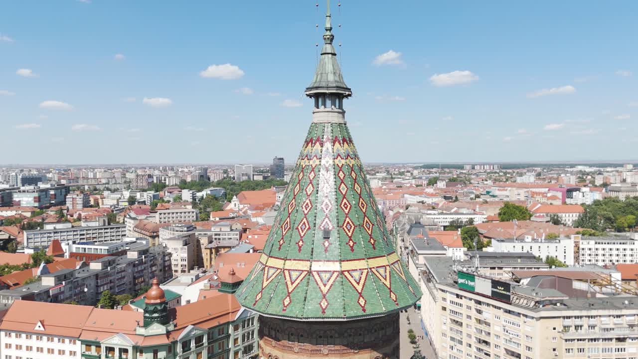 Smooth aerial orbit highlighting the ornate spire of the Metropolitan Cathedral with panoramic views of Timisoara behind it