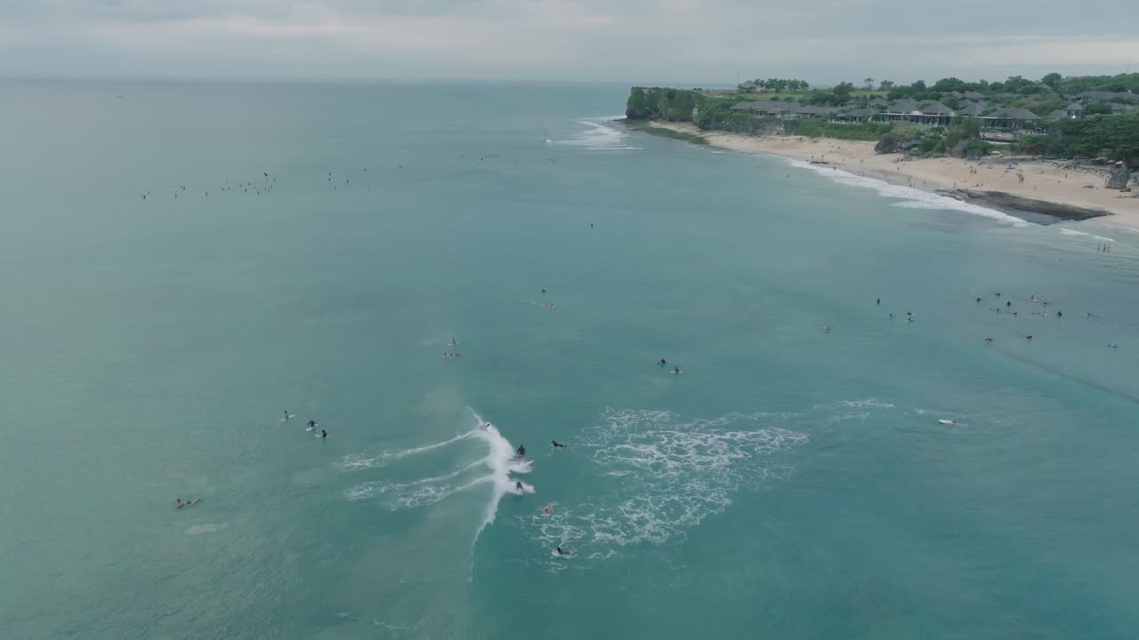 drone de la playa de dreamland, bali, uluwatu indonesia en la hora dorada al atardecer con agua turquesa y surfistas