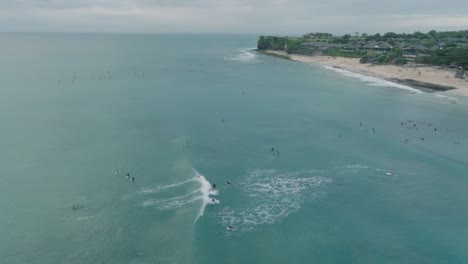 Drone-of-Dreamland-Beach,-Bali,-Uluwatu-Indonesia-at-golden-hour-sunset-with-turquoise-water-and-surfers