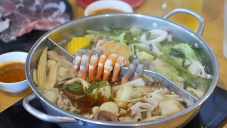 pov de video de 4k mientras se pone carne de cerdo en una olla caliente shabu shabu llena de vegetales y carne