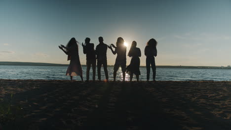friends dancing on the beach at sunset