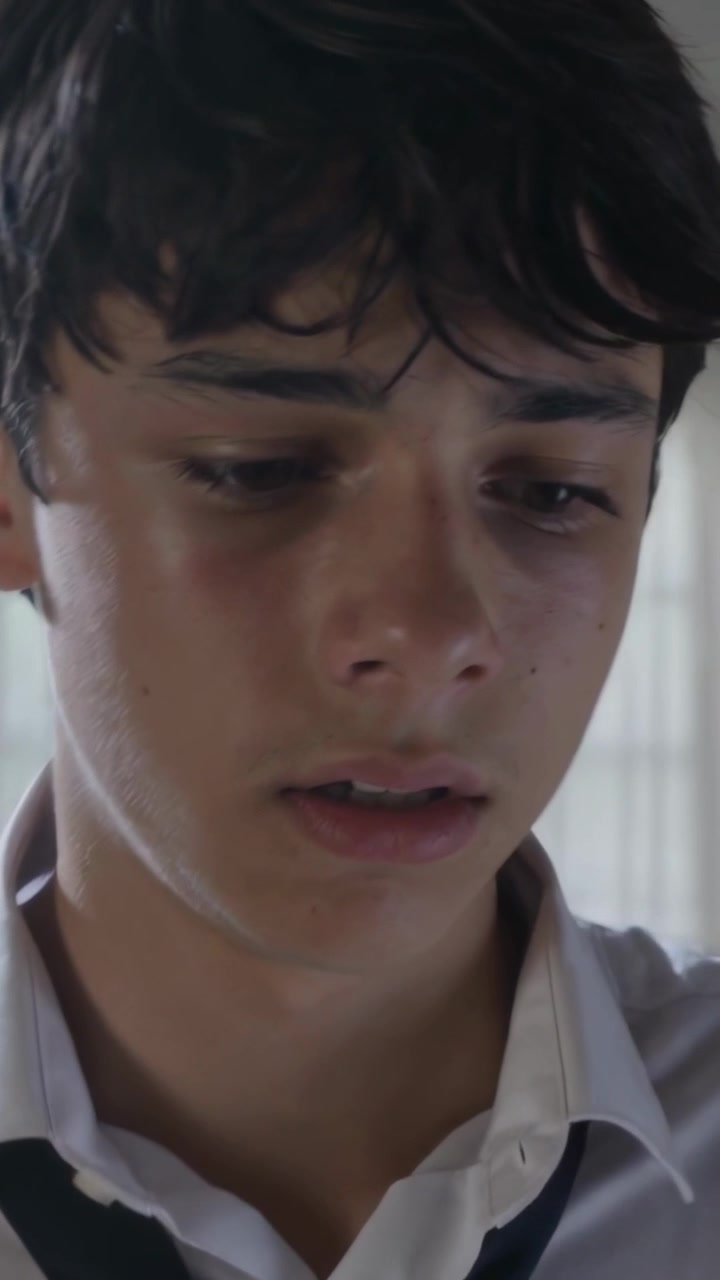 Video verticale: Adolescente che abbassa lo sguardo mentre la telecamera si avvicina alle finestre della scuola, con gli occhi lucidi, cravatta allentata