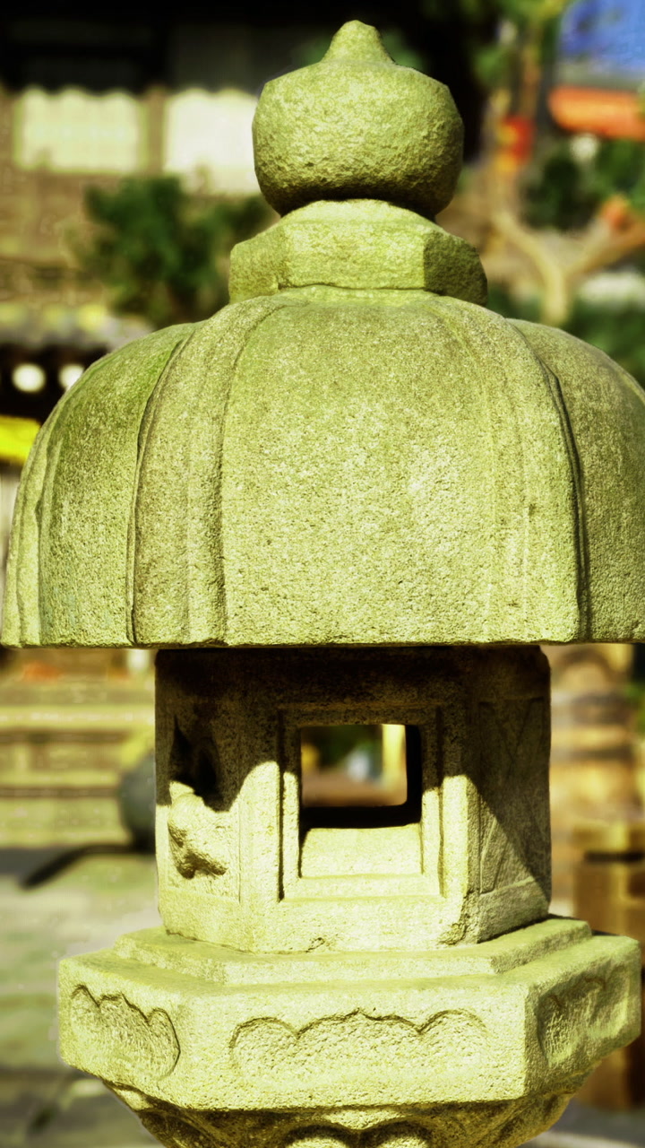 Stone lantern stands in a garden under clear blue sky during daytime