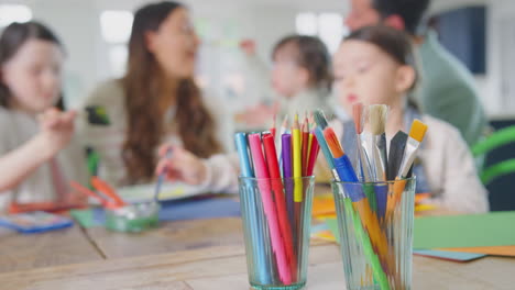 Nahaufnahme-Von-Pinseln-Und-Bleistiften,-Während-Eine-Familie-Mit-Down-Syndrom-Tochter-Zu-Hause-Am-Tisch-Sitzt-Und-Gemeinsam-Bastelt