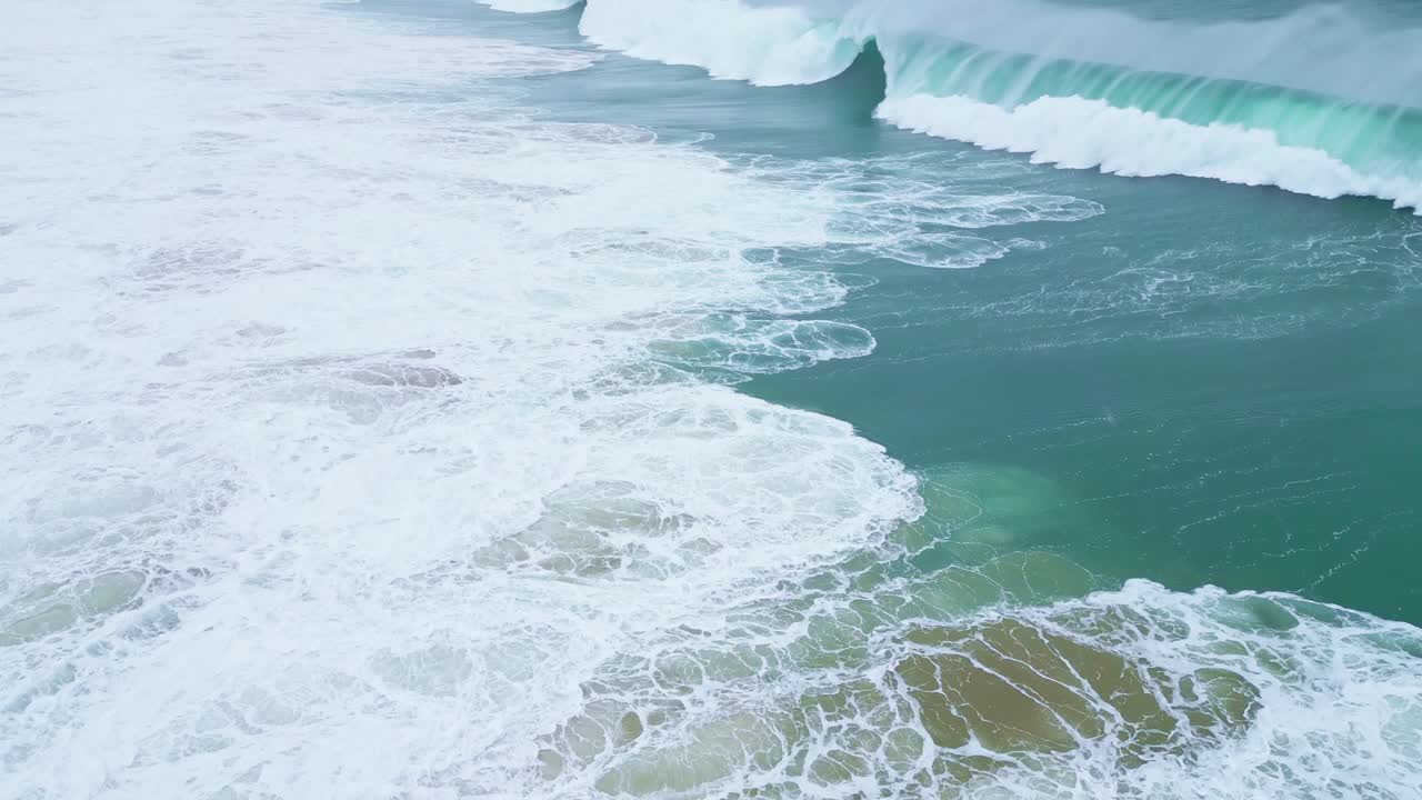 White foam crashing against the shore in slow motion at Aljezur, Portugal