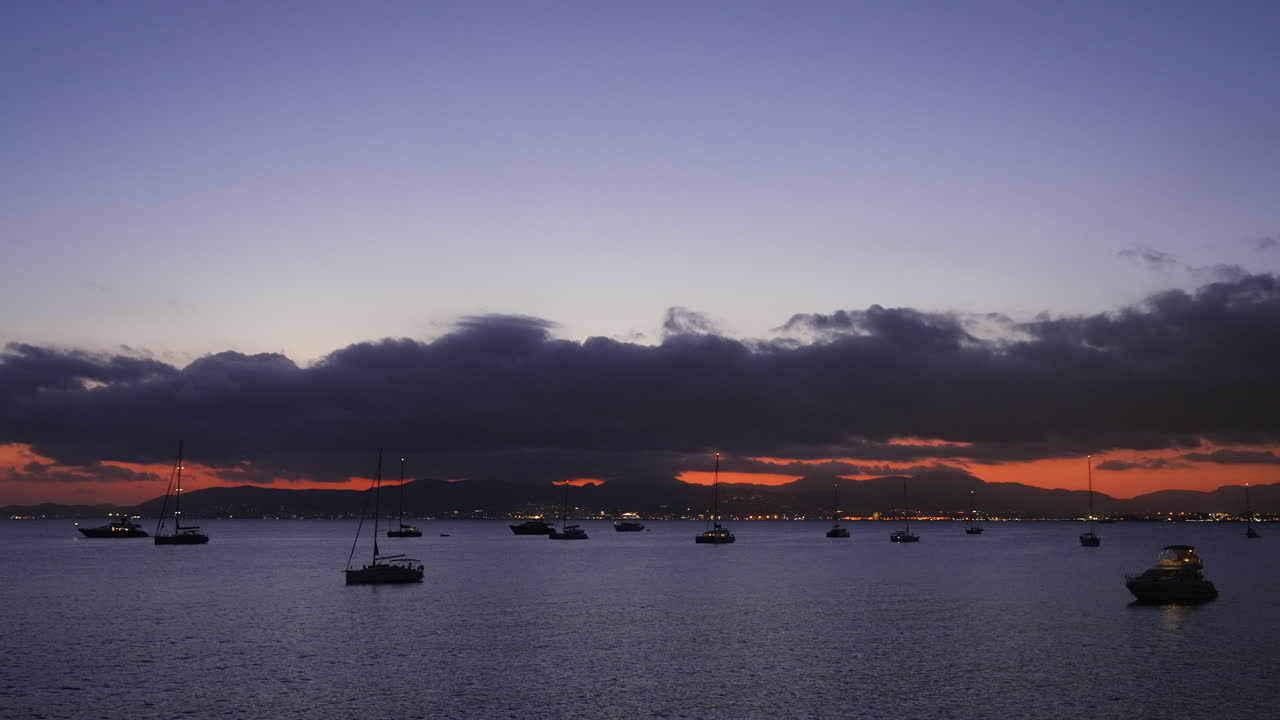Cielo al tramonto rosso e nuvoloso e rilassante su yacht che galleggiano lungo la costa mediterranea di Maiorca.