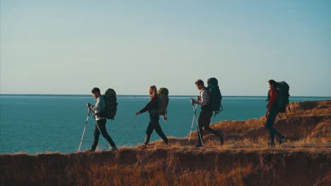 the four hikers walking on the mountain near the sea. slow motion