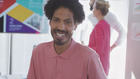 Portrait-of-happy-biracial-businessman-over-diverse-colleagues-in-office