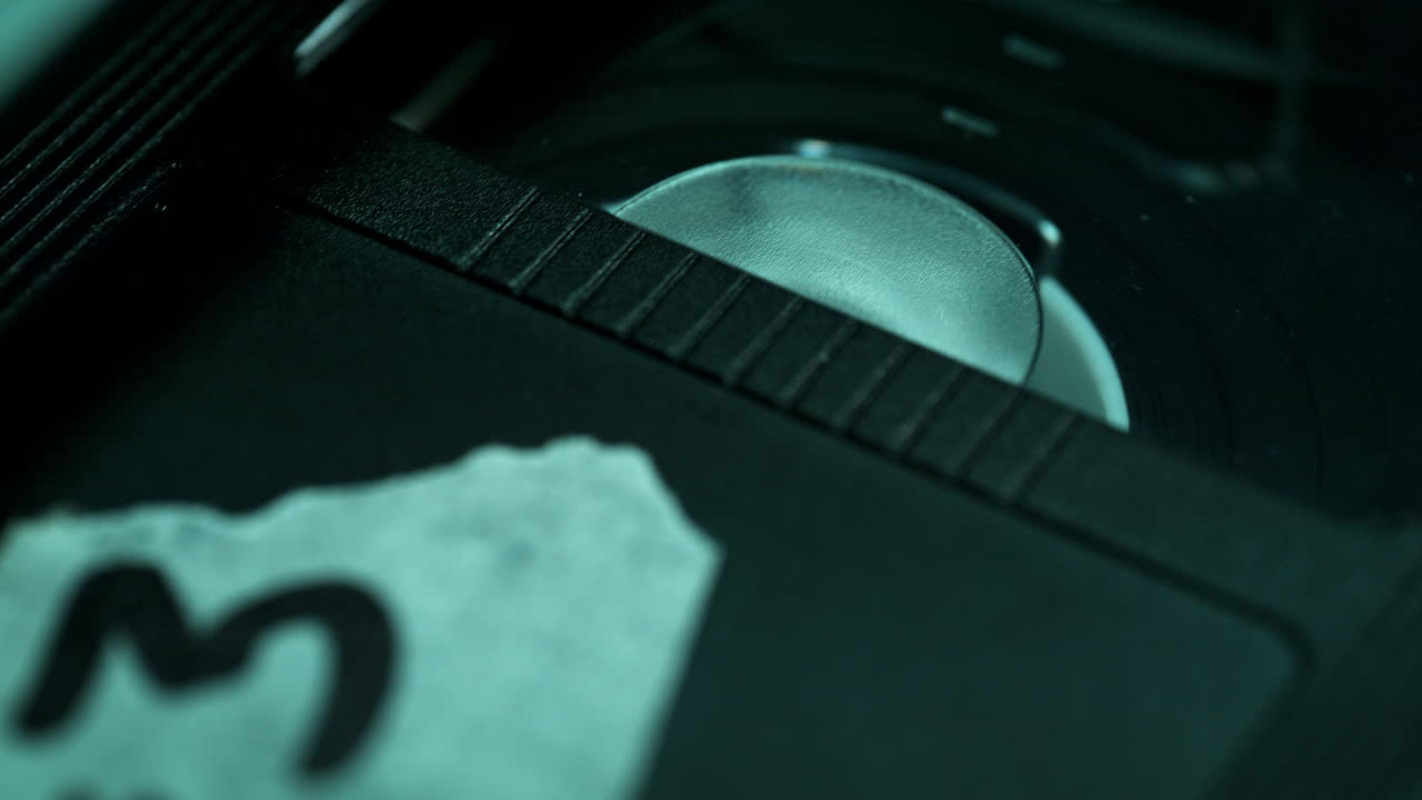 Etichetta della cassetta VHS su nastro video in riproduzione in macro - Rallentatore sul guscio di plastica della cassetta, atmosfera scura da sala interrogatori