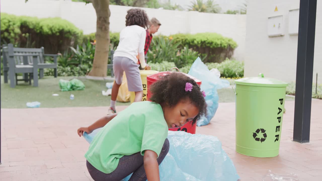 학교  ⁇  에서 쓰레기 를 재활용 하기 위해 쓰레기 를 모으는 세 명 의 다양한 학교 자녀 들 의 영상