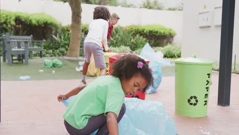 video de tres escolares diversos recogiendo basura para reciclar en el patio de la escuela