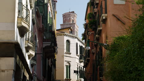 typical facade exterior of buildings on narrow street canal in venice, italy