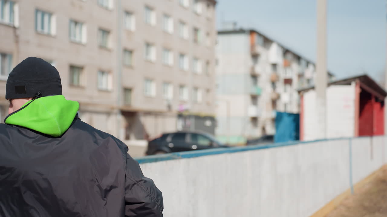 울타리 옆에서 전략을 논의하며 장벽에 기대어 서 있는 흰색 십 대 팀 동료들, 옆에는 축구공, 배경에는 아파트 건물, 계획에 집중하고 친근하게 협업하는 모습, 차분한 팔레트와 솔직한 분위기