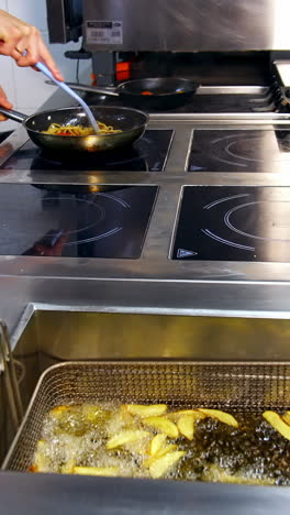 deep fryer in the kitchen restaurant. chef is cooking food in the frying pan. crispy potatoes frying in hot boiled oil. delicious meals. vertical video