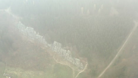 aerial shot of clouds covering beautiful mountain landscape, green trees and rock wall