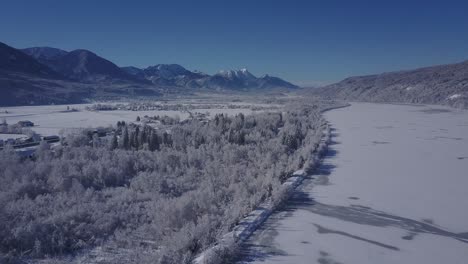 4k aerial video view of alpine snowy valley forest road and frozen river in peak of winter overflight - drone collection stock video