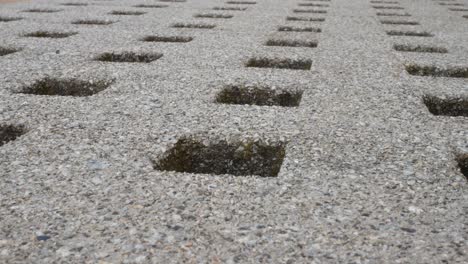 low angle repeated geometric stone square holes carved in granite marble surface dolly left