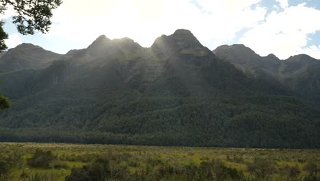 Sun-rising-from-behind-the-mountains-shining-on-Fiordland-National-Park-mirror-lakes