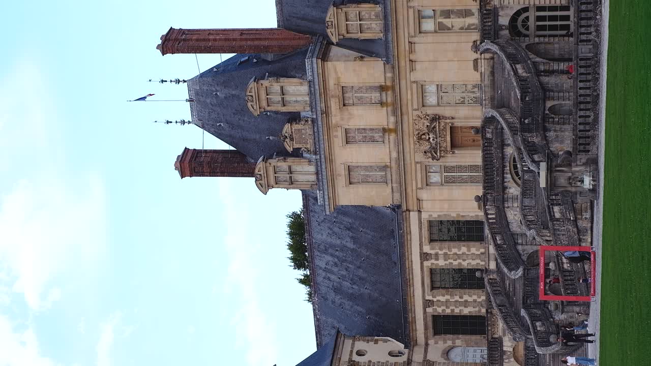Fontainebleau, France - April 21, 2021: People walking in front of the Chateau de Fontainebleau castle in daylight. Vertical