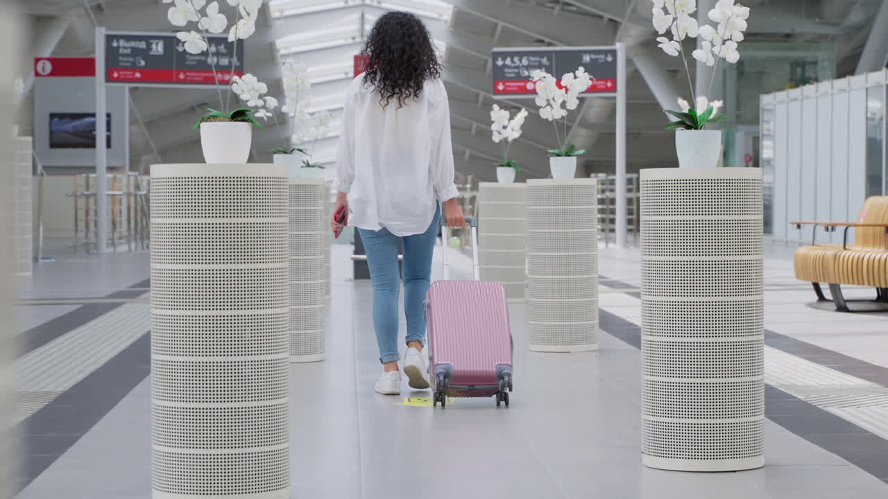 mujer caminando por la terminal del aeropuerto con una maleta