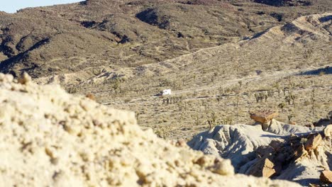 un vehículo recreativo conduce a través del accidentado paisaje del desierto de mojave en el parque estatal red rock canyon de camino a un campamento