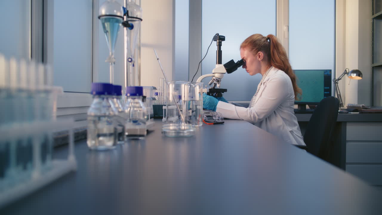 científica que usa un microscopio en un laboratorio