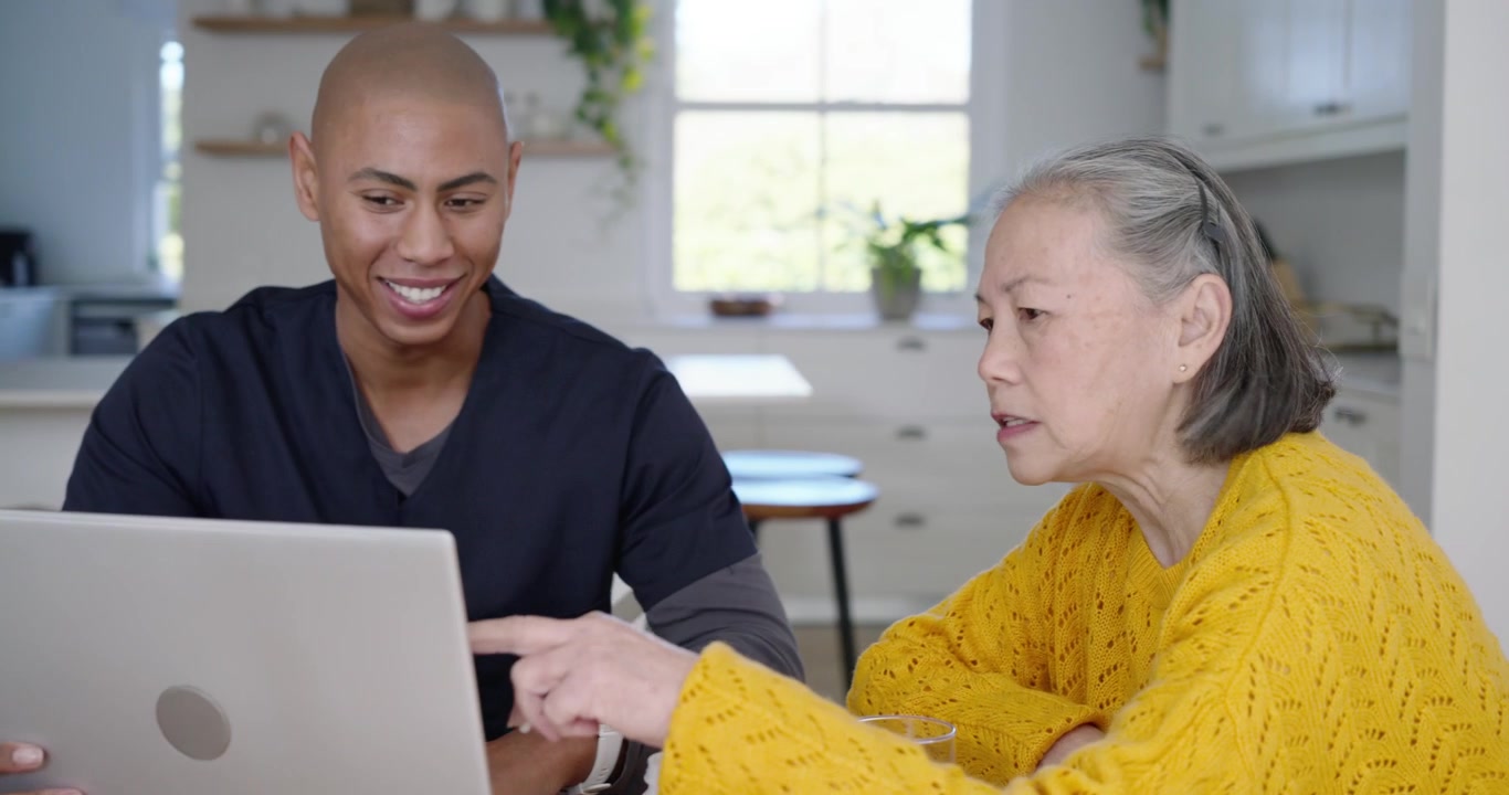 Senior Chinese woman and African aide opening laptop checking bottle taking pill and drinking water