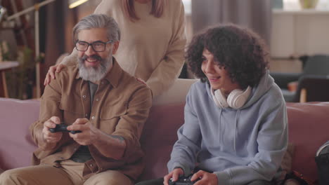 mujer abrazando a su marido e hijo mientras juegan a un juego de consola