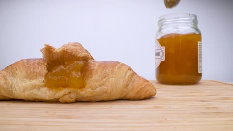 macro view of woman putting marmalade into croissant