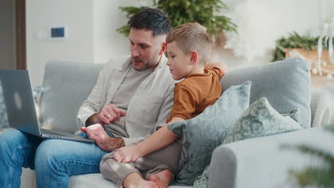 papá enseñando a un niño cómo navegar por internet en una computadora portátil durante la navidad