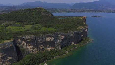 aerial shot closing in to the cliffs of manerba at lago di garda on a bright sunny day