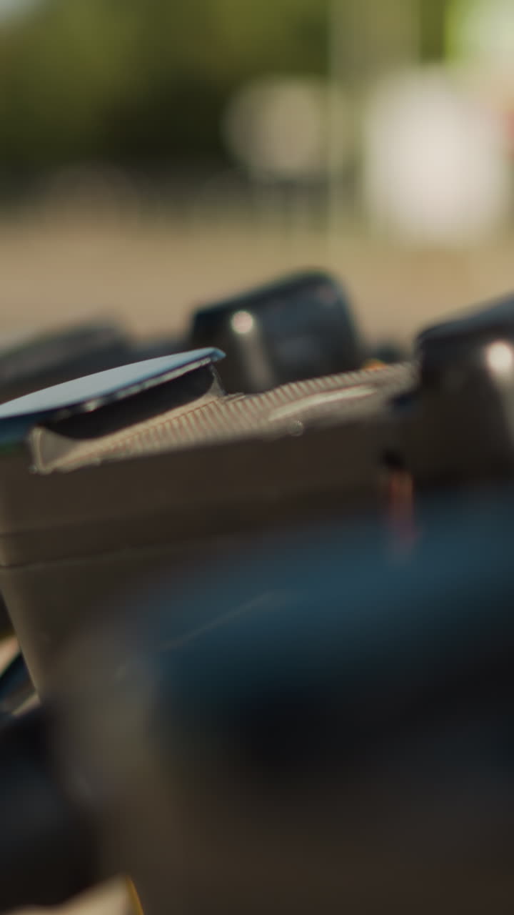 primer plano del panel del manillar que muestra el panel texturizado y los botones de control, poca profundidad de campo con reflejos bokeh, reflejos iluminados por el sol sobre el metal, ambiente de inspección que sugiere mantenimiento técnico