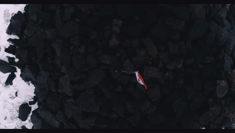 Drone-footage-flying-up-in-a-rocky-shore-showing-a-man-holding-the-Indian-Flag