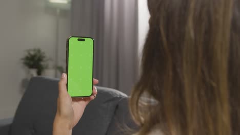 over the shoulder shot of woman using green screen mobile phone 1