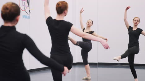 female students at performing arts school rehearsing ballet in dance studio reflected in mirror