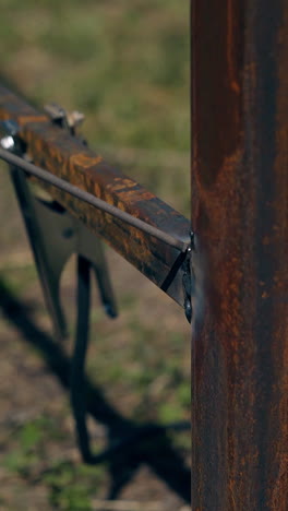 closeup handyman welds thin bottom rusty rail to fence carcass with powerful instrument on daytime