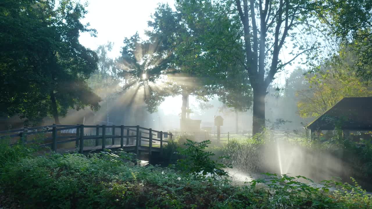 A tranquil morning scene with sunbeams and a water fountain