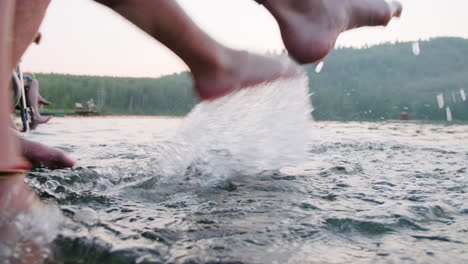 legs of couple splashing lake water with feet