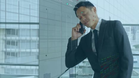 Animation-Der-Datenverarbeitung-An-Der-Börse-über-Einem-Asiatischen-Geschäftsmann,-Der-Im-Büro-Auf-Dem-Smartphone-Spricht